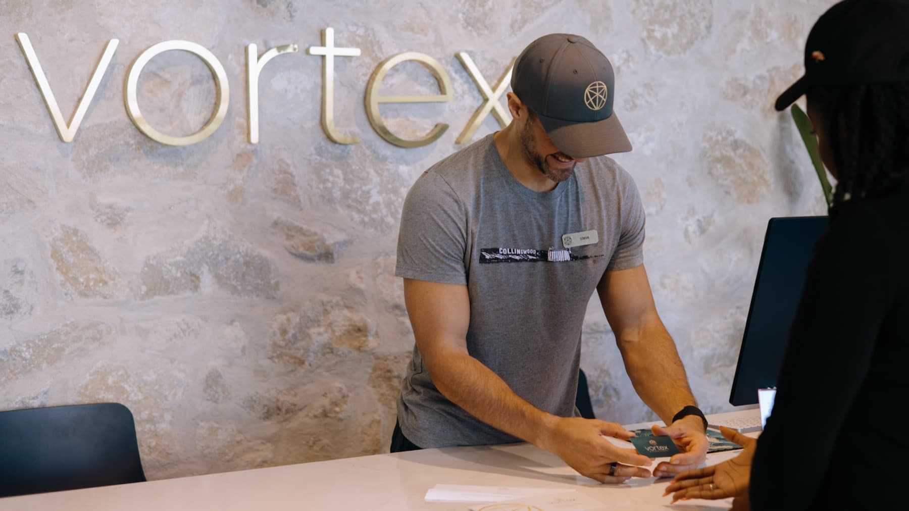 A Vortex team member handing a gift card across the front desk